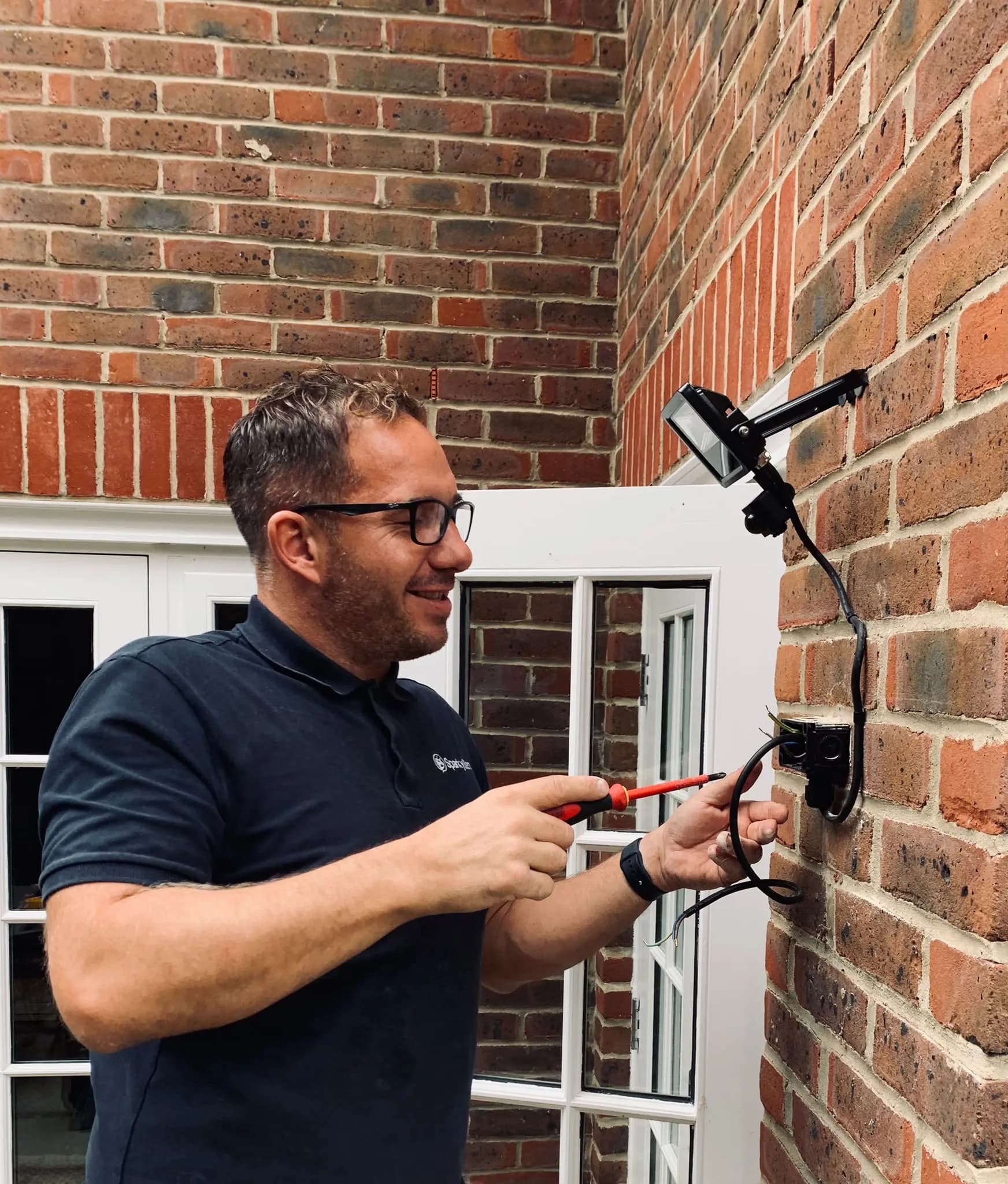Ben working on an outdoor wall light on a brick wall