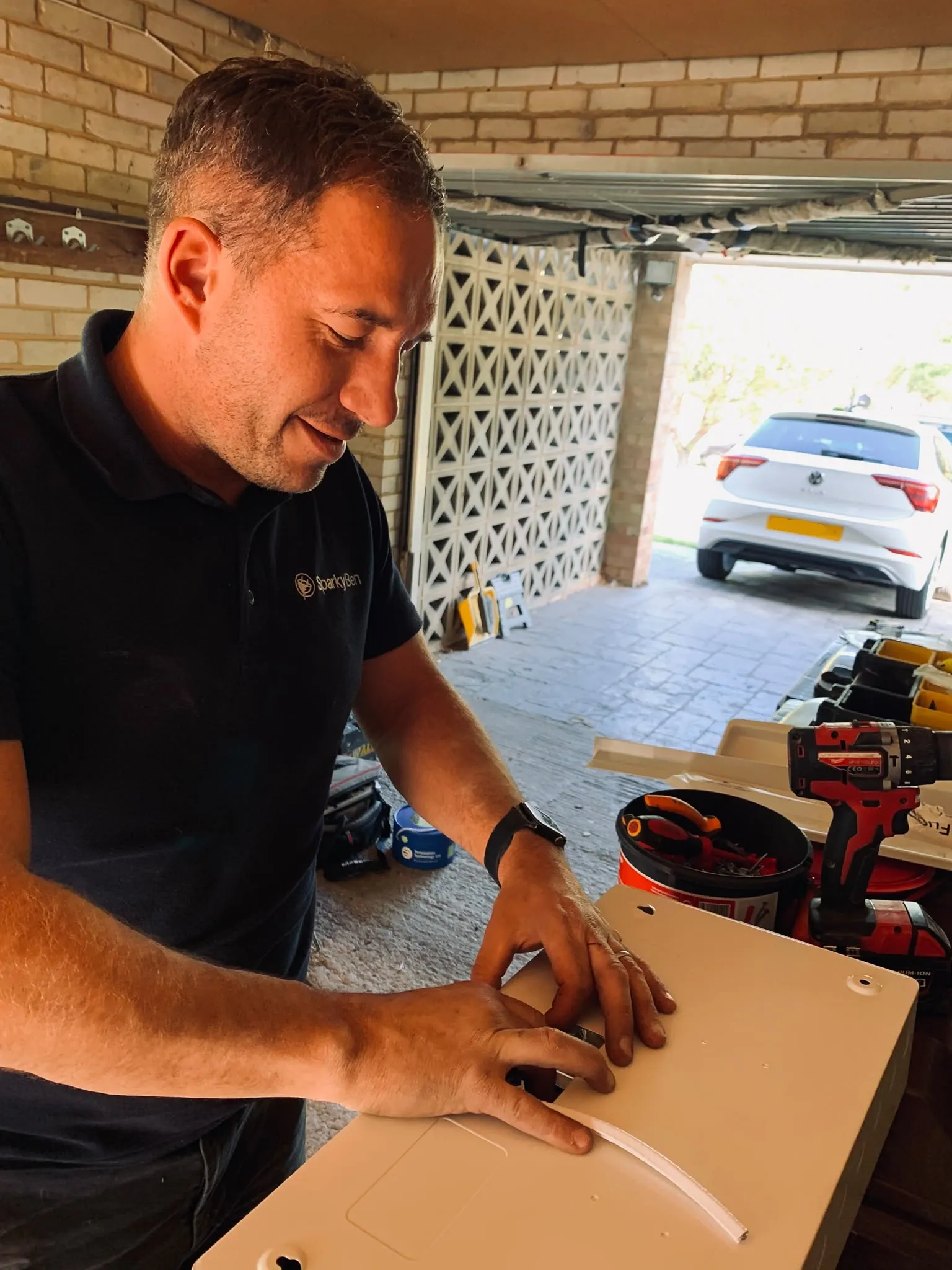Ben preparing a consumer-unit cover in a garage