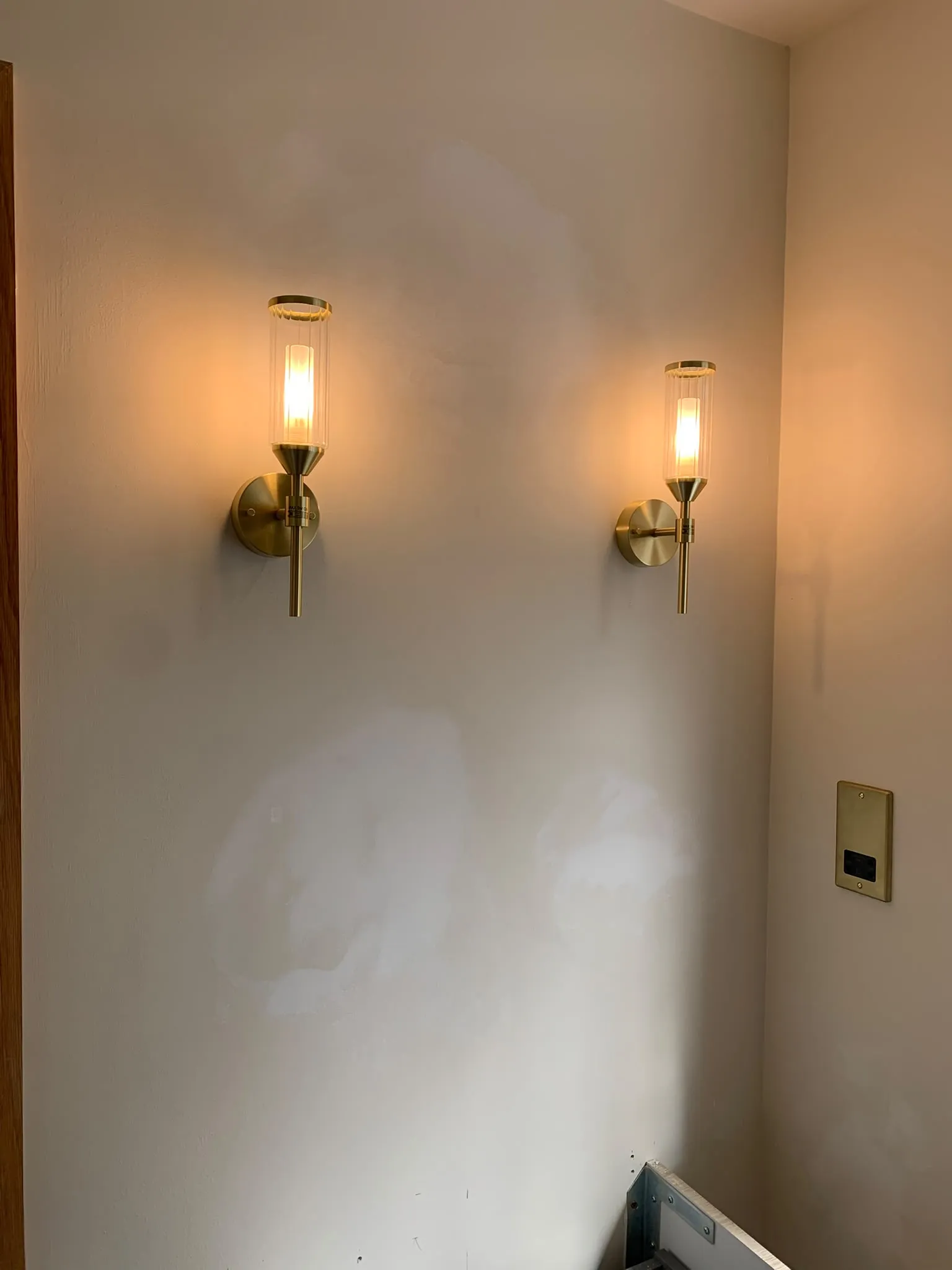 Two brass wall lights switched on after installation